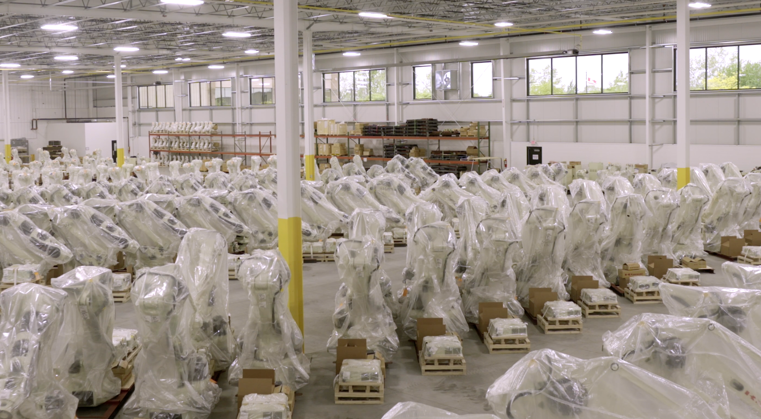 A spacious indoor room filled with numerous plastic bags scattered across the floor and hanging from the walls, creating a visually striking display reminiscent of an art installation in a factory setting.