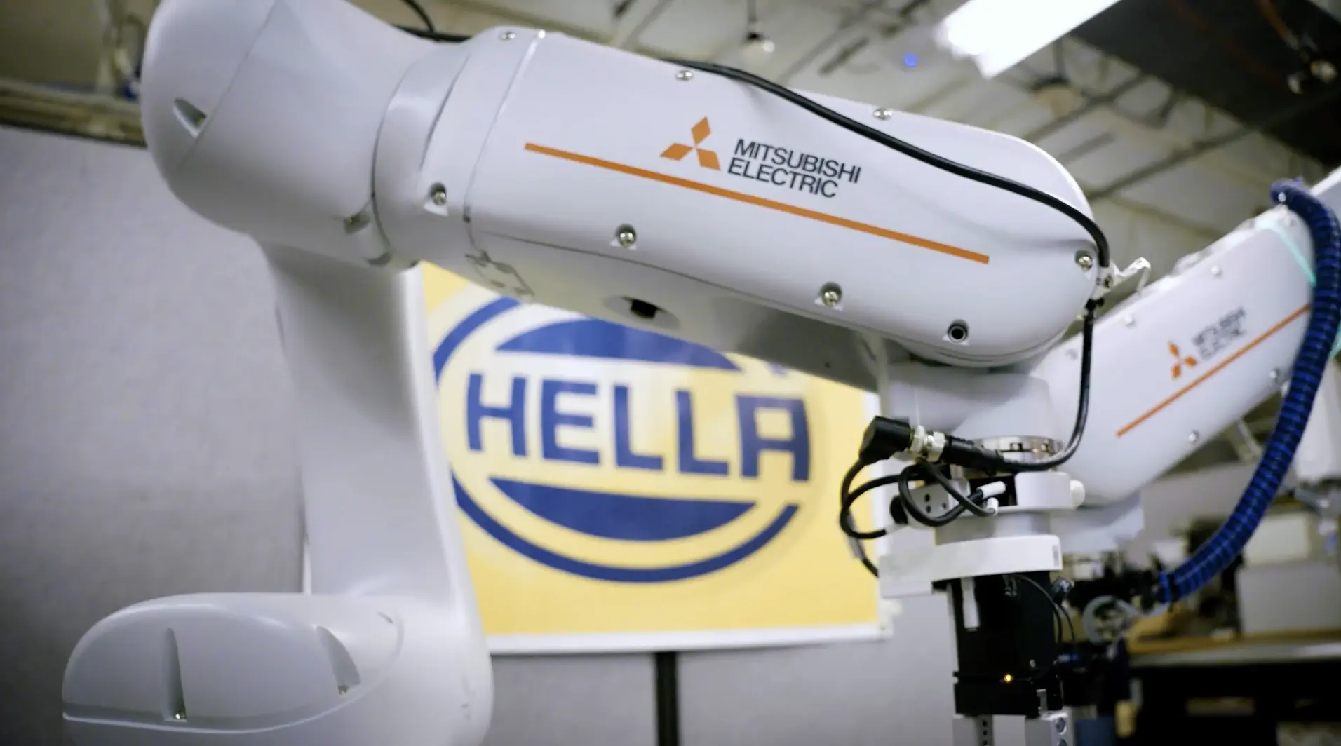 A white and blue airplane with branding from Mitsubishi Electric and Hella, positioned indoors near a telescope.