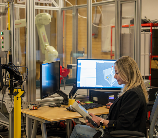 Woman working at a computer with a robot in background