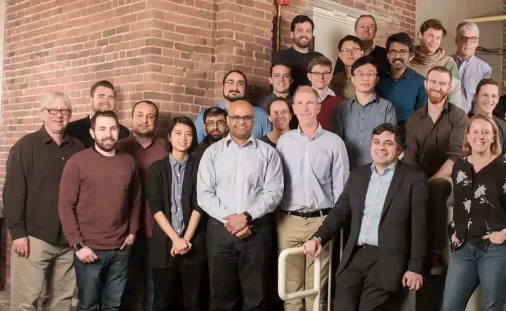 A collaborative team of individuals standing together in front of a brick wall